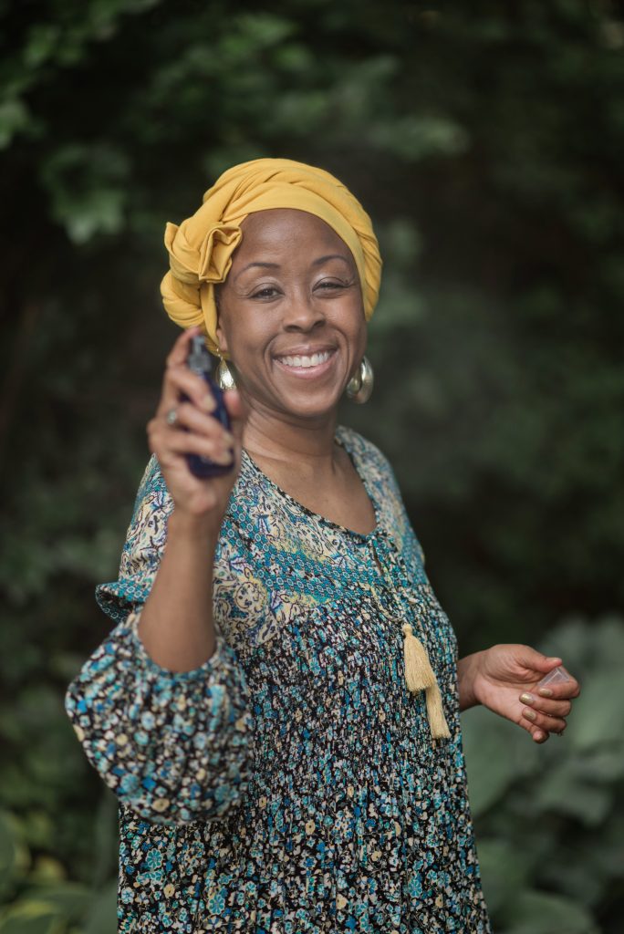 Danyielle Nelson smiling and holding an essential oil bottle