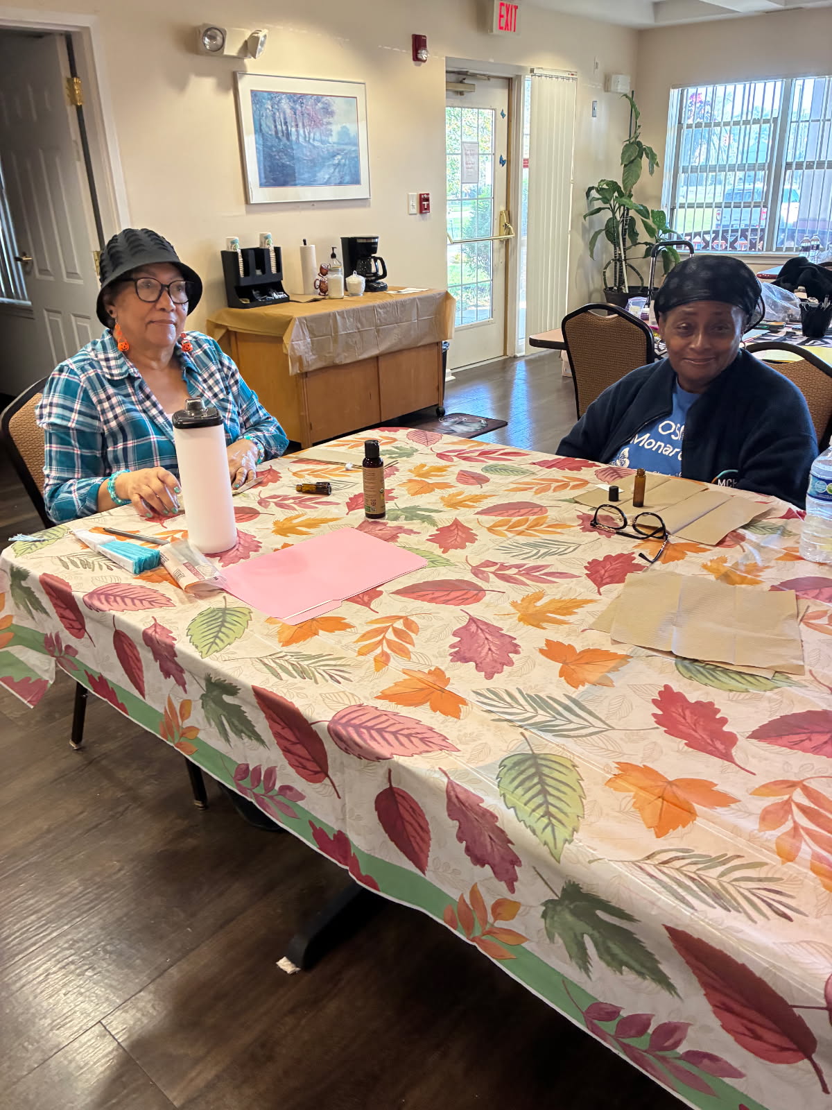 Two workshop guests seated at a table with roller bottle supplies and a bottle of Frankincense essential oil