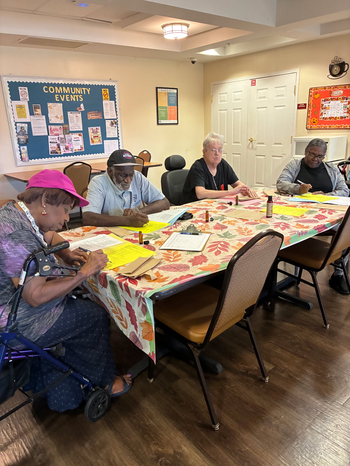 Seniors seated at a workshop table filling out handouts with amber roller bottles in front of them
